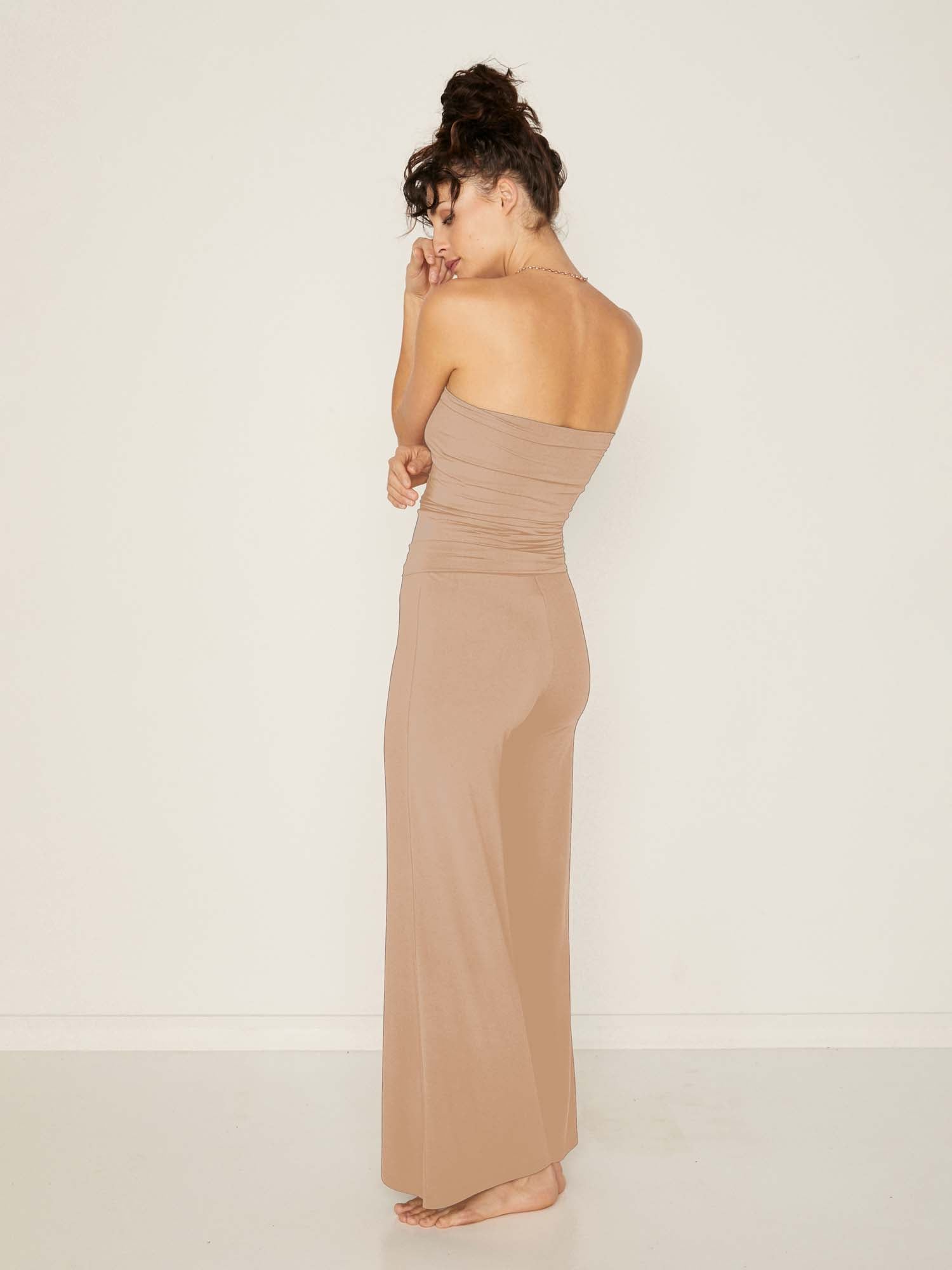 Model wearing caramel full length palazzo pants, fitted waist and hips with flowing wide leg, adjustible high waistband, women's bamboo clothing