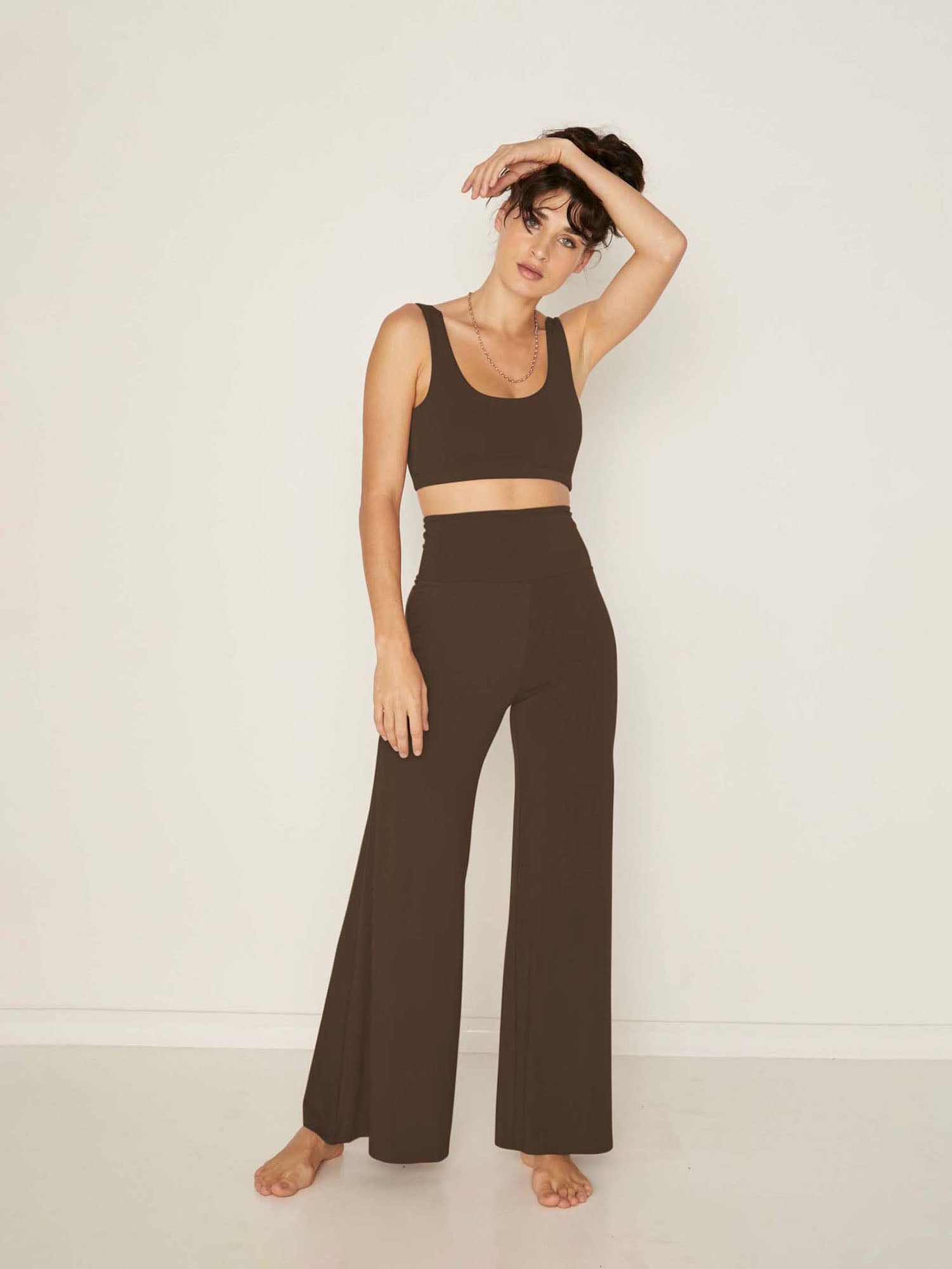 Model wearing cocoa full length palazzo pants, fitted waist and hips with flowing wide leg, adjustable high waistband, women's bamboo clothing