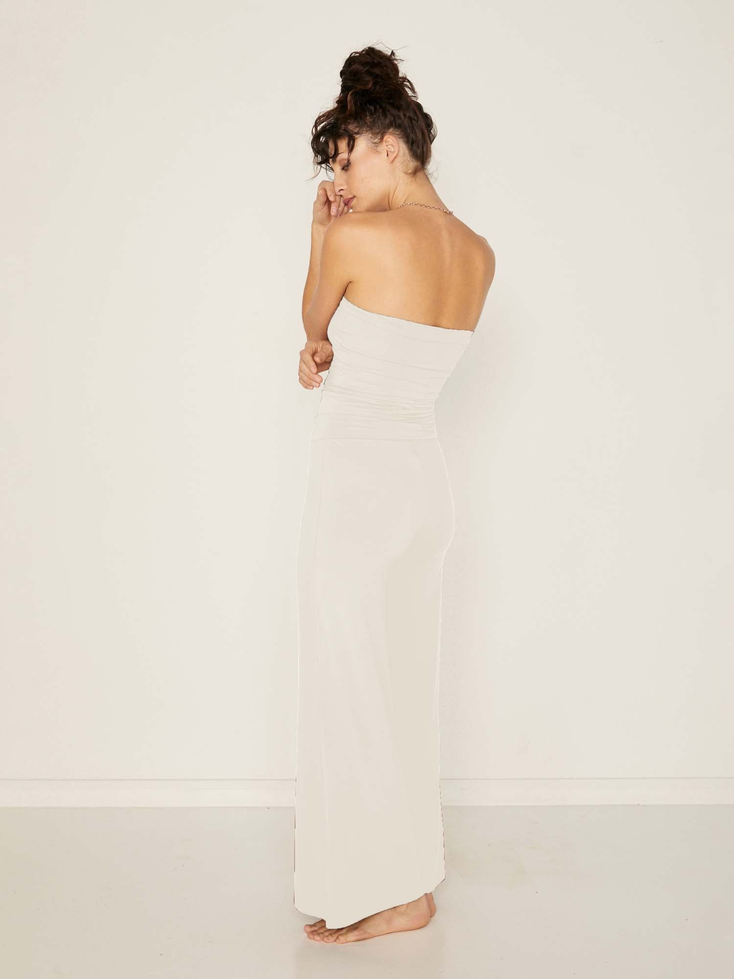 Model wearing cream full length palazzo pants, fitted waist and hips with flowing wide leg, adjustible high waistband, women's bamboo clothing