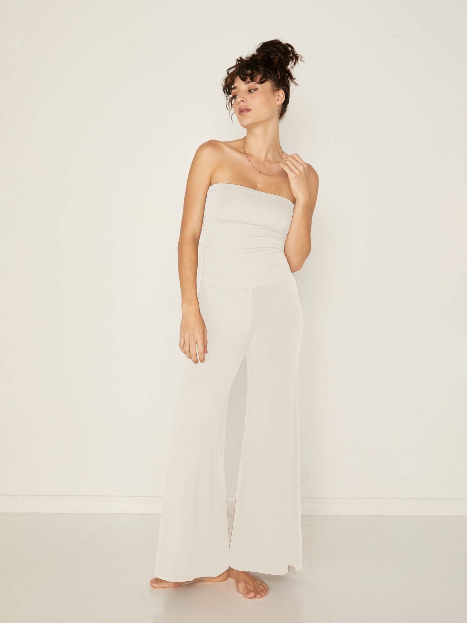 Model wearing cream full length palazzo pants, fitted waist and hips with flowing wide leg, adjustible high waistband, women's bamboo clothing