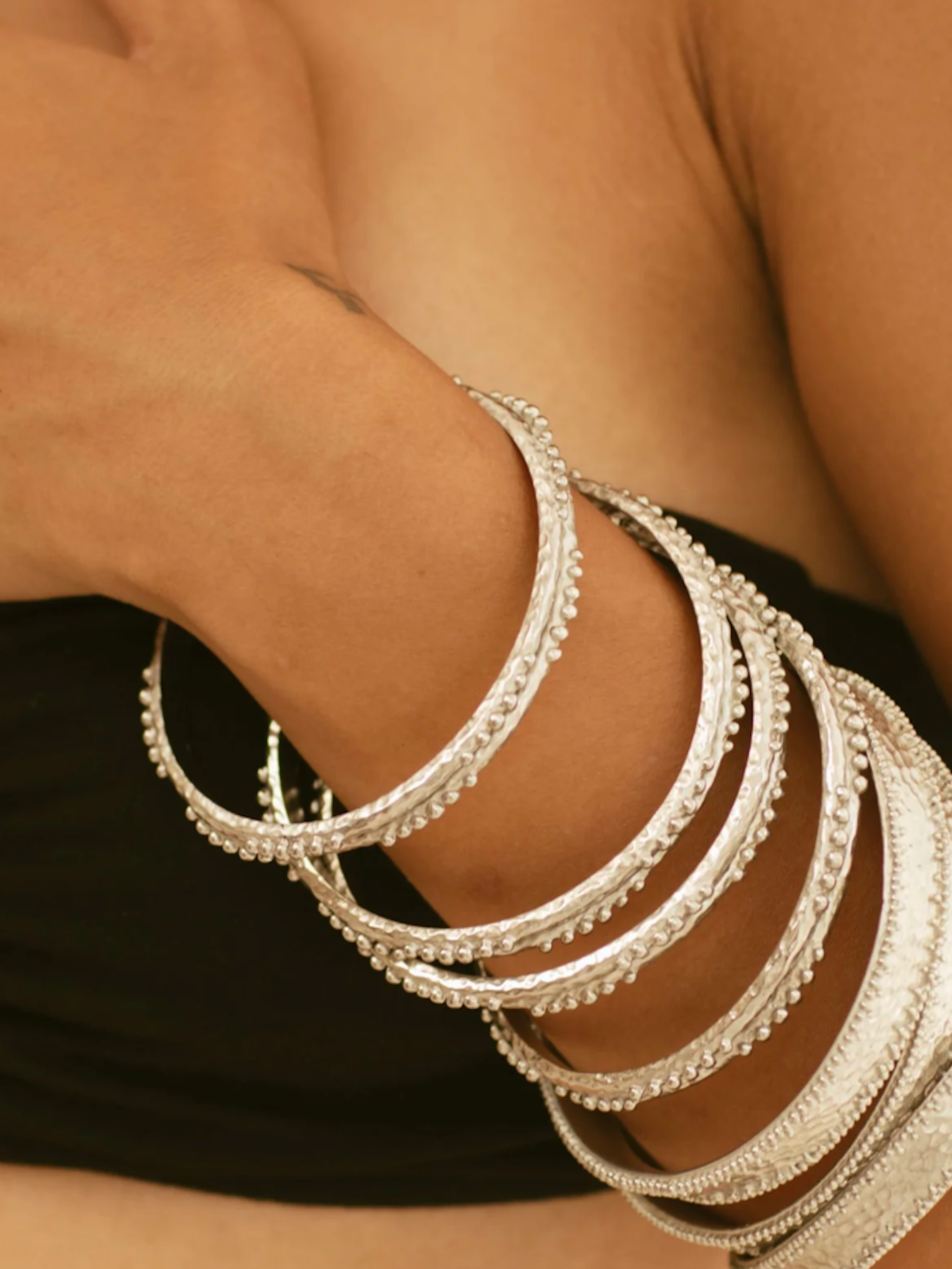 Silver bangles on a wrist with a blurred background